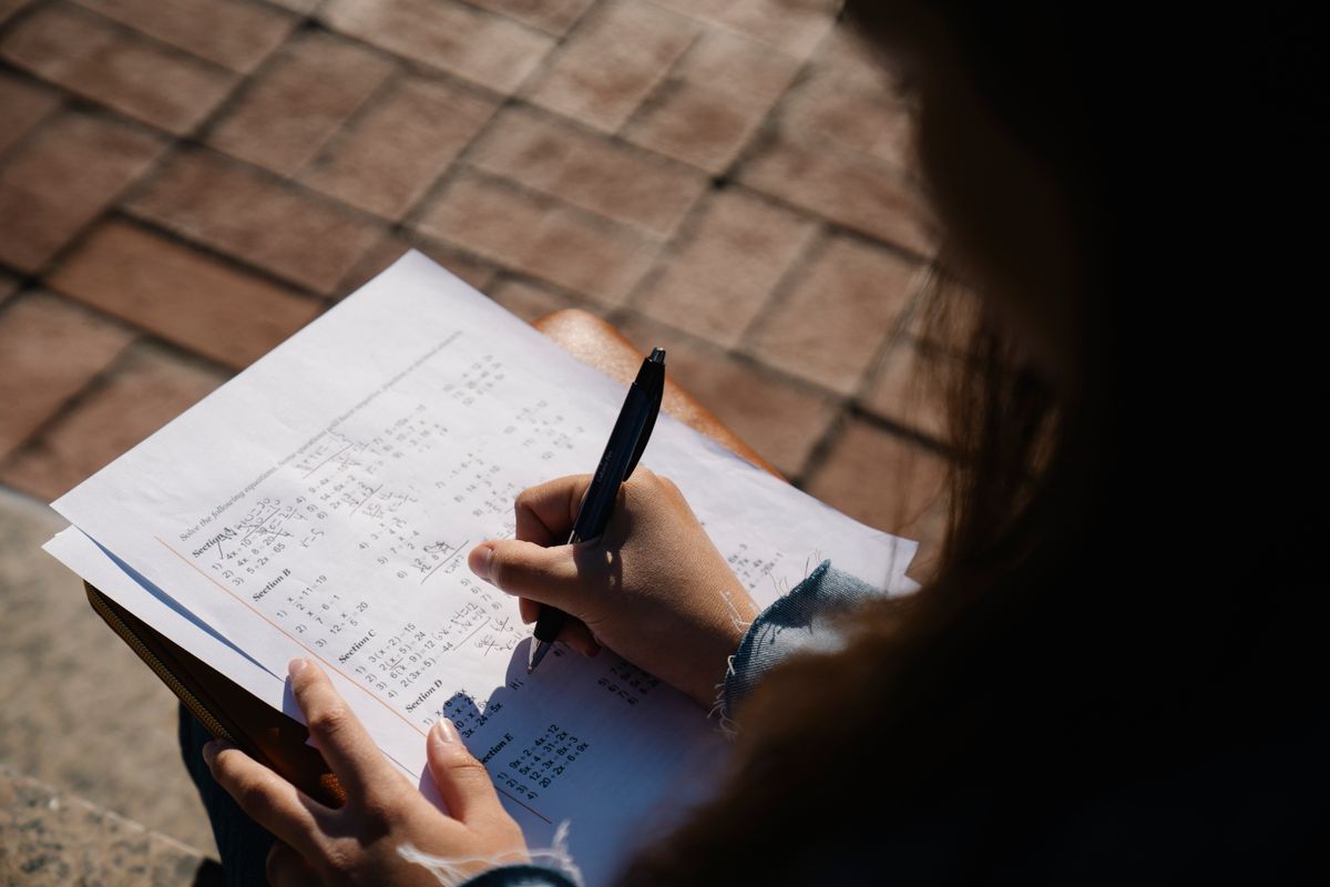 Candidat qui résout des exercices de calcul sur une feuille pour préparer le GMAT